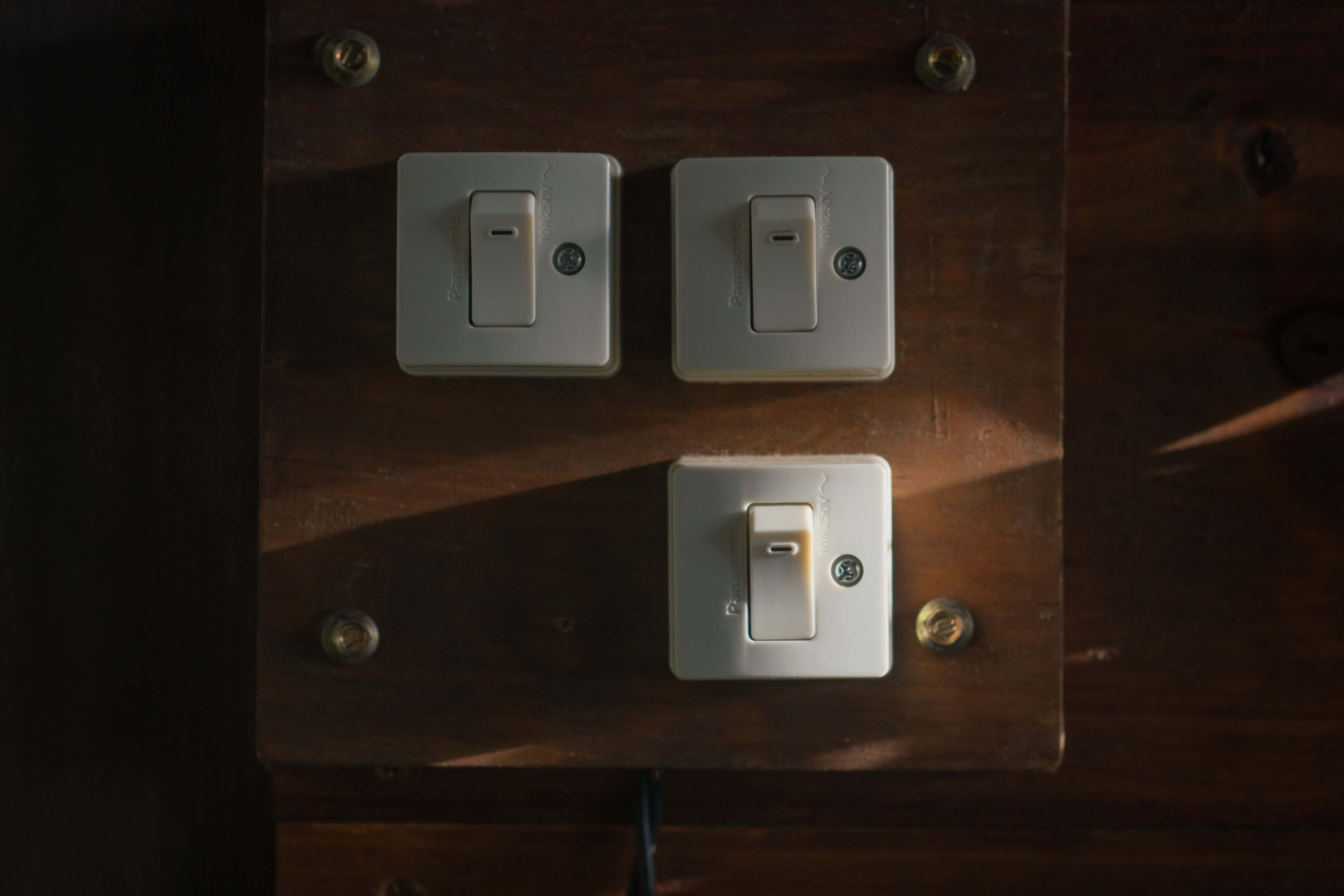 Illuminated light switches in a dim interior setting, close-up on a wooden panel